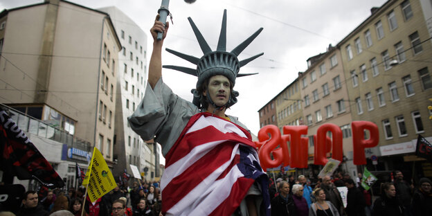 Foto einer Anti-TTIP-Demo, ein Mann verkleidet als Freiheitsstatue