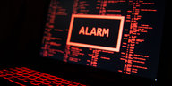 Auf einem Laptop ist in roter Schrift auf schwarzem Hintergrund das Wort „Alarm“ zu sehen