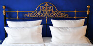 Hotelbett mit vielen Kissen vor blauer Wand