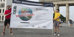 Zwei Aktivisten halten Schild mit Aufschrift "Erde nicht verfügbar" vorm Brandenburger Tor hoch