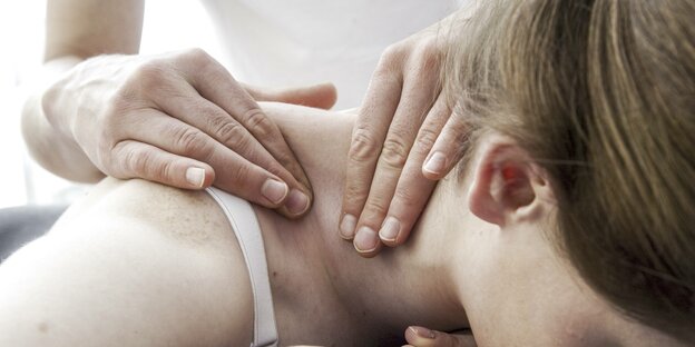 Hände einer Physiotherapeutin bei Nackenmassage