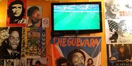 Ein Fernseher mit Fußball auf dem Bildschirm hängt zwischen politischen Plakaten