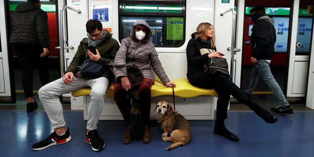 Ein Mann, zwei Frauen und ein Hund sitzen in der U-Bahn