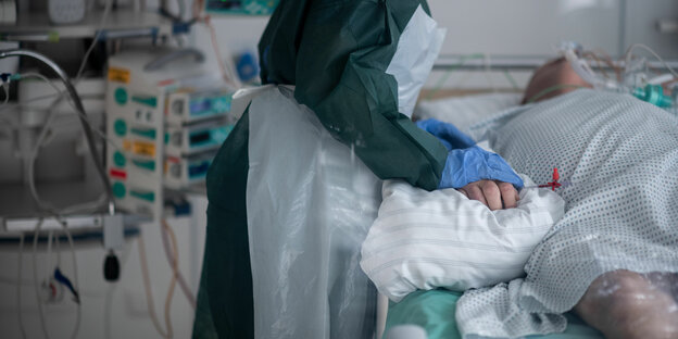Eine Pflegekraft hält einen Patienten im Krankenhaus die Hand