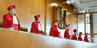 Die Mitglieder des zweiten Senats des Bundesverfassungsgerichts stehen in roter Robe unter dem hölzernen Bundesadler im Gerichtssaal