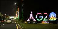 Leuchtschrift gefaltete Hände und G20 Logo am Rande einer Straße in der Nacht