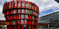 Auffällige Architektur, die sich kubisch nach oben hin weitet und rote mit grünen Farben verbindet