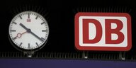 Logo der Deutschen Bahn neben einer Uhr auf dem Bahnsteig