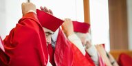 RichterInnen des Bundesverfassungsgerichts in roten Roben setzen ihre rote Haube auf