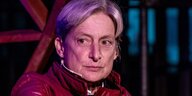 Judith Butler diskutierend auf einem Podium mit roter Lederjacke