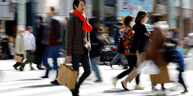 Japaner:innen gehen auf einer Straße mit Einkaufstüten