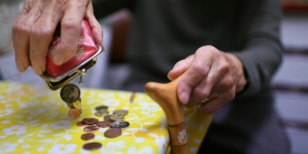 Eine Rentnerin schüttet den Inhalt ihres Geldbeutel auf den Küchentisch.