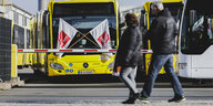 Menschen laufen an einem BVG-Bus mit Verdi-Bannern vorbei