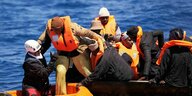 Motorsegler helfen Migranten aus einem kentergefährdeten, überfüllten Stahlboot in ihr Dinghi umzusteigen.