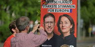 Freiwillige hängen ein SPD Wahlplakat auf.