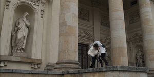 Zwei Menschen raufen neben den Säulen einer Kathedrale