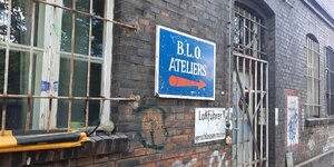 Ein Schild mit der Aufschrift "BLO Ateliers" an einer Mauer zeigt den Weg an.